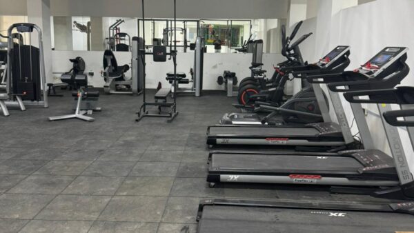 Spacious gym with treadmills, stationary bikes, weight machines, and mirrors on the wall.