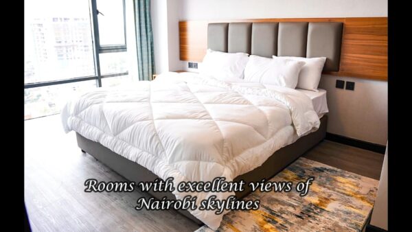 Modern hotel room with a plush bed, large window offering Nairobi skyline views, and stylish decor.