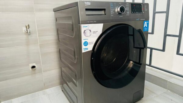 Silver front-loading washing machine with digital display, side panel, and visible steam and energy rating labels.