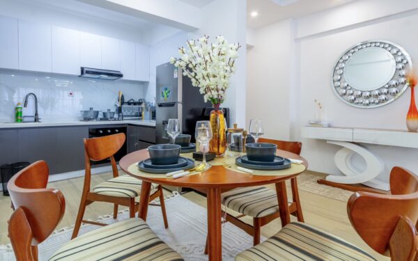 Modern kitchen with a round dining table set for four, featuring a vase of white flowers and stylish decor accents.